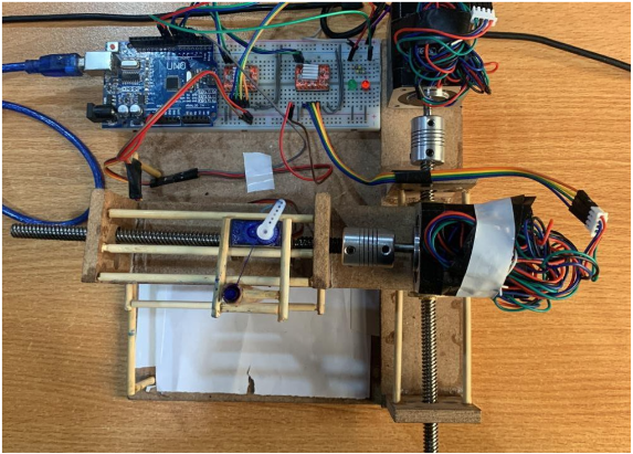 The finished Arduino 2D printer build, showing the Arduino UNO, breadboard, stepper motors, servo, and wooden frame
